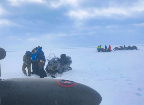Rescuers escort a cold musher toward a waiting Alaska National Guard helicopter/ANG photo